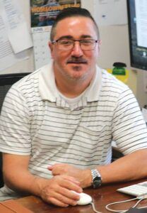a picture of Chris Meche, owner of christianmerch.net, at his desk